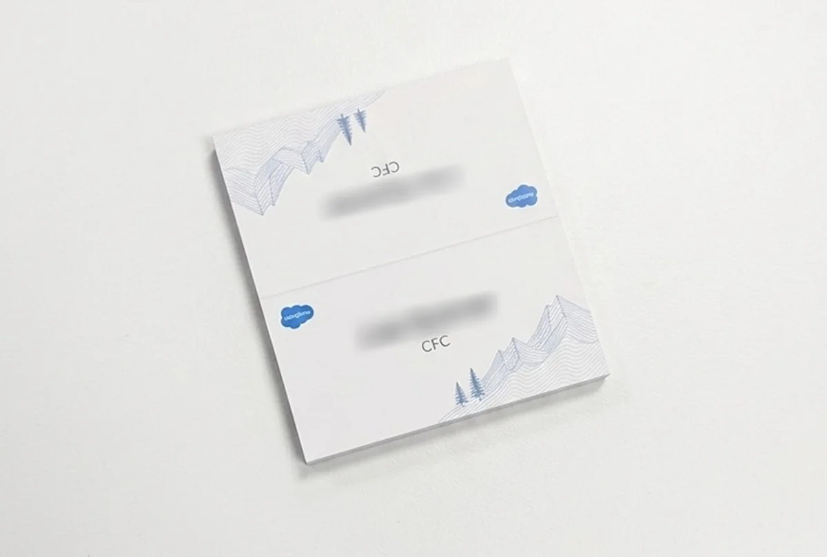 Stack of printed place cards, the top one open flat, with a guest name set on both panels either side of the fold