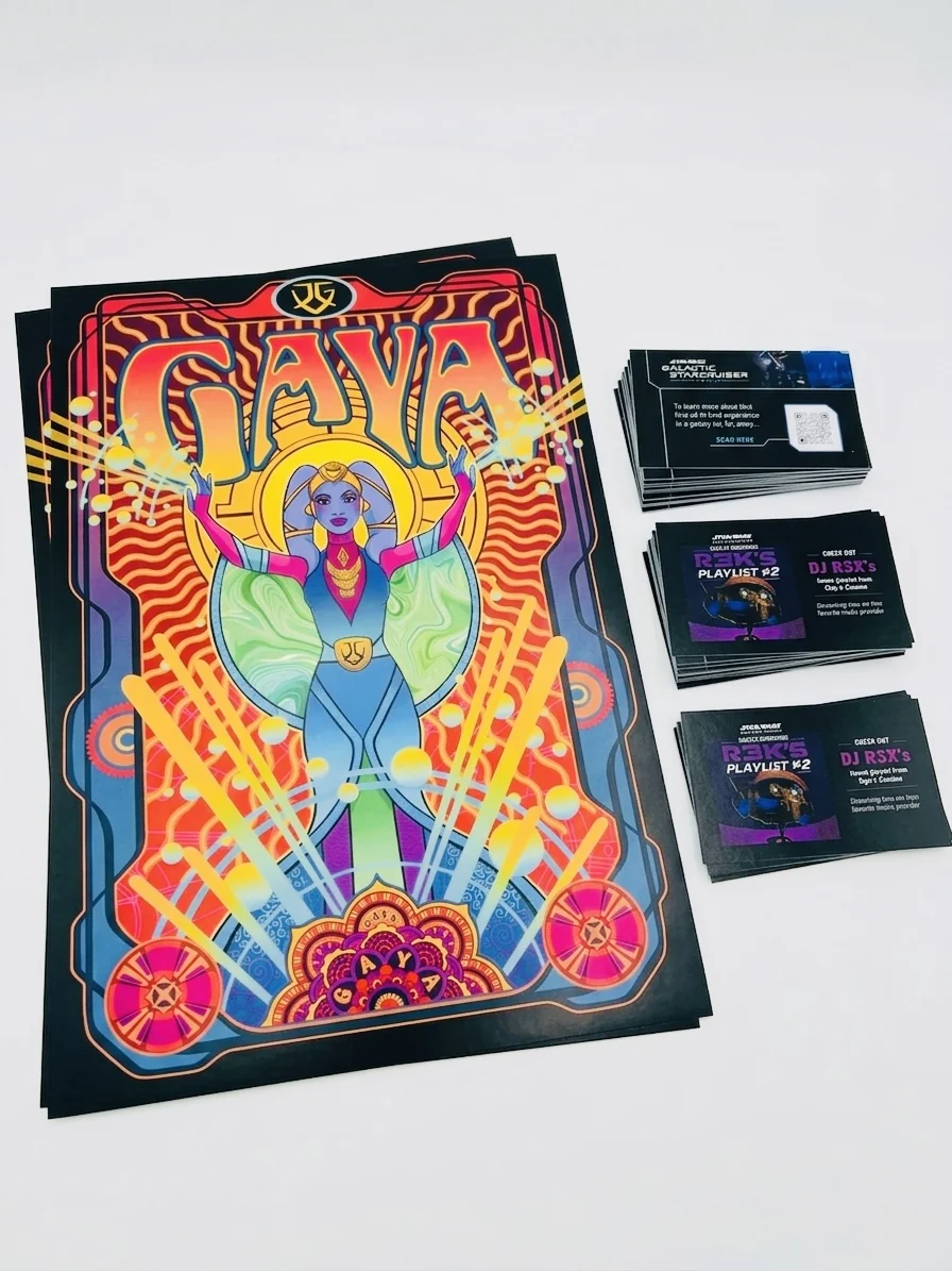 A Gaya concert poster on top of a printed stack, beside three piles of Star Wars Celebration QR giveaway cards