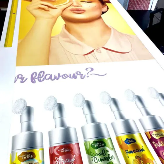 Long Wash a Brush banner on the bench showing foam cleanser bottles and a model holding an orange