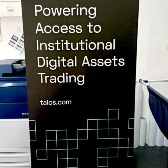 Black Talos roller banner reading Powering Access to Institutional Digital Assets Trading, beside a press