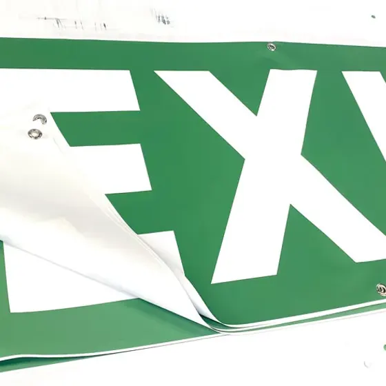 Green fire exit banner photographed close up with one corner curled back