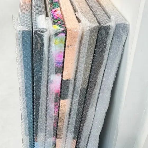 Several stretched canvases stood on edge, each wrapped in bubble wrap