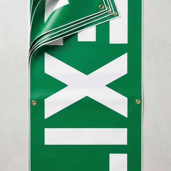 A green EXIT banner fixed to a wall with one top corner folded forward