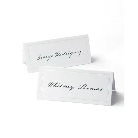 Two white folded place cards printed with guest names in a script typeface