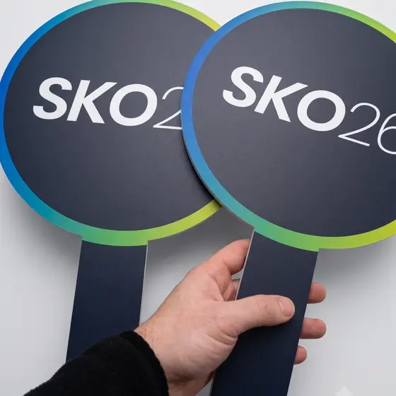 A hand holding two round handheld event paddles with a gradient border