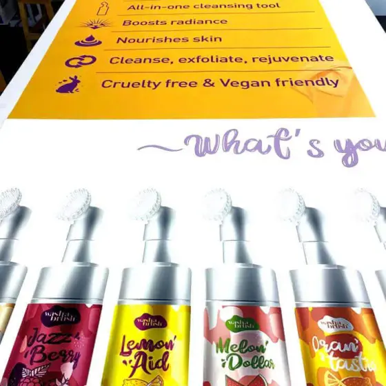 A large yellow printed poster standing behind a row of branded cosmetic bottles