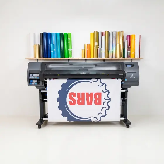 A wide format latex printer with a printed graphic on the roll and coloured vinyl rolls on a shelf above