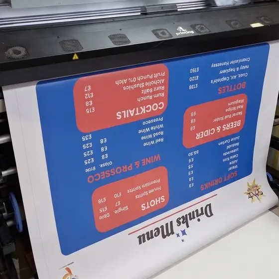A printed menu emerging from a wide format printer, blue with red panels