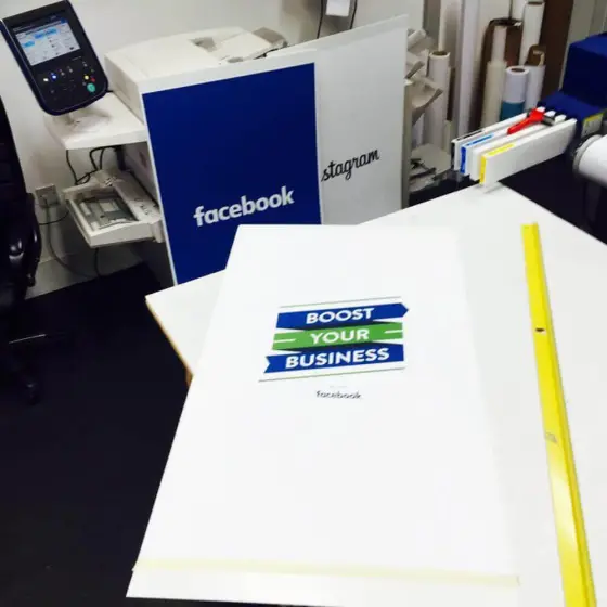 A freshly mounted display board on the finishing bench, printed Facebook and Instagram boards stacked behind