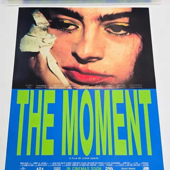 A large format portrait poster in blue and green, the top edge still curled from the roll