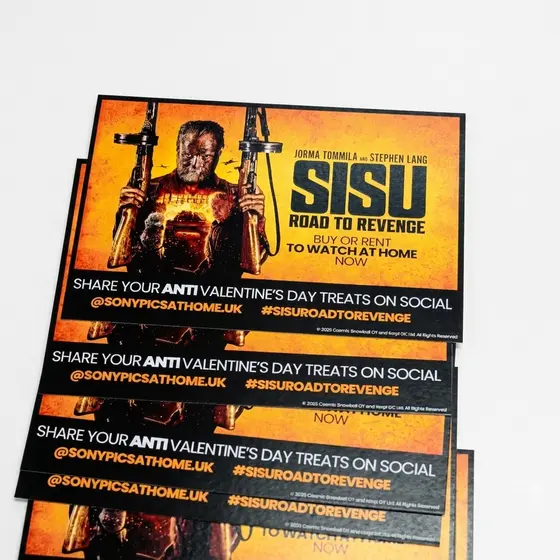 Promotional cards for a film release, stacked and fanned, orange and black
