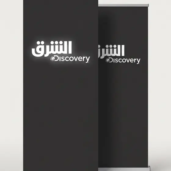 Two black roller banners with Arabic broadcast branding, standing against a plain wall
