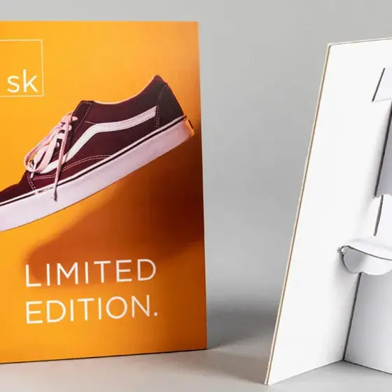 An orange retail strut card showing a trainer, photographed front and back with the strut folded out