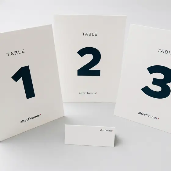 Three folded table number cards standing in a row with a place card in front