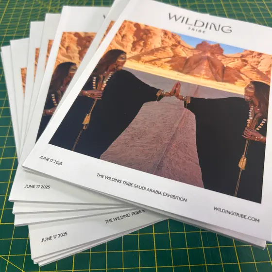 A stack of saddle-stitched exhibition catalogues fanned out on a green cutting mat