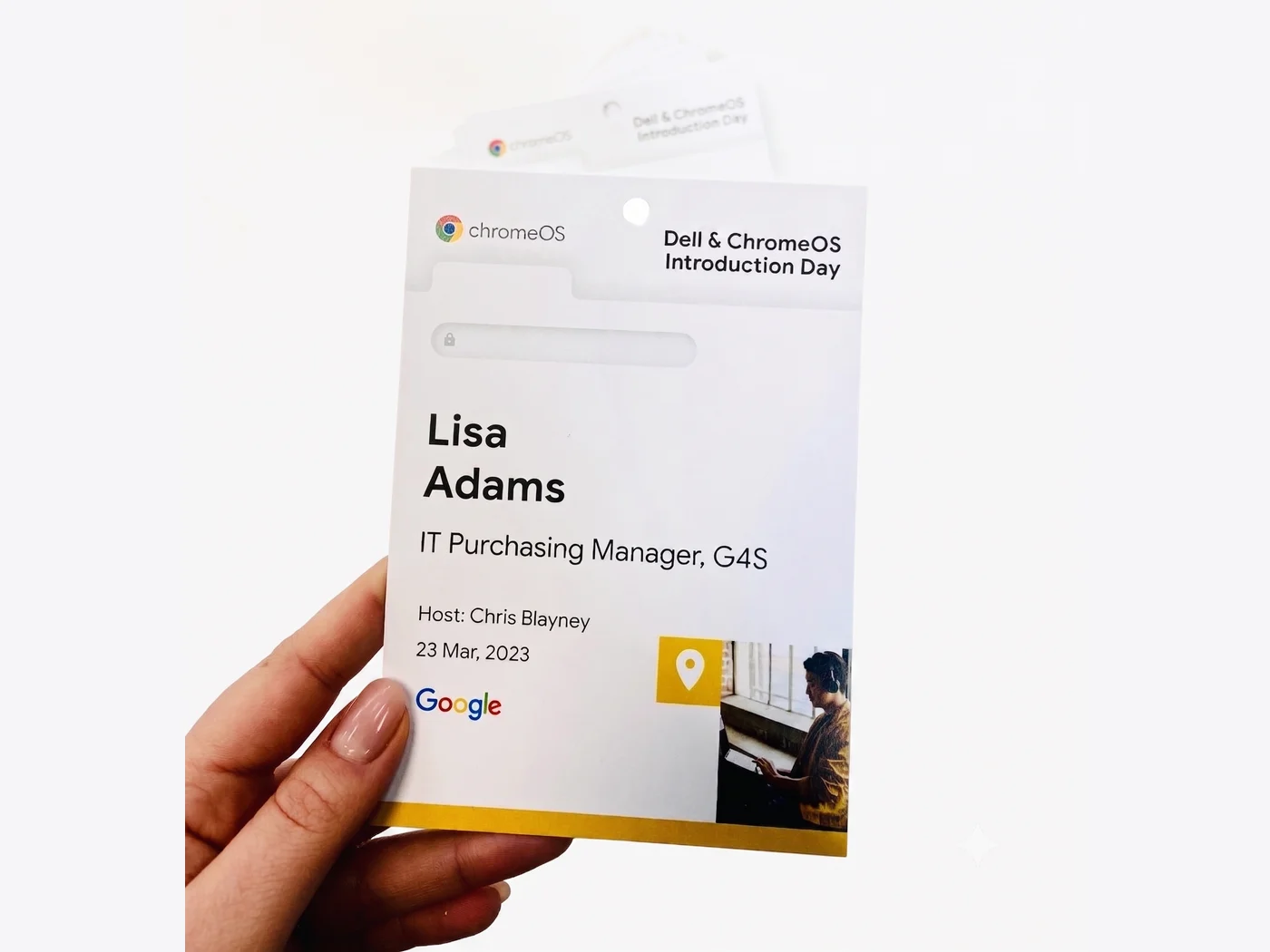 Hand holding a printed conference badge reading Lisa Adams, IT Purchasing Manager, punched for a lanyard
