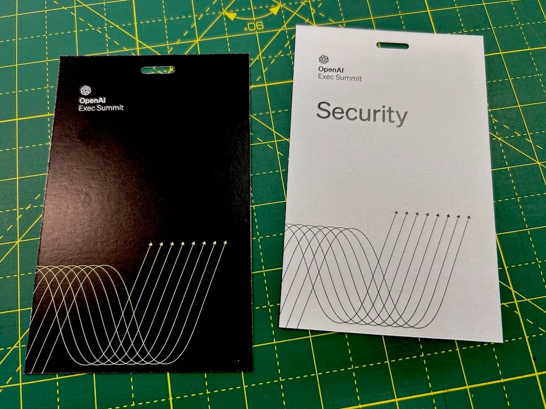 Black and white event badges on a green cutting mat, one printed Security, both hole punched