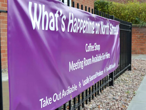 Purple banner reading What&rsquo;s Happening in North Devon, fixed to black railings outdoors