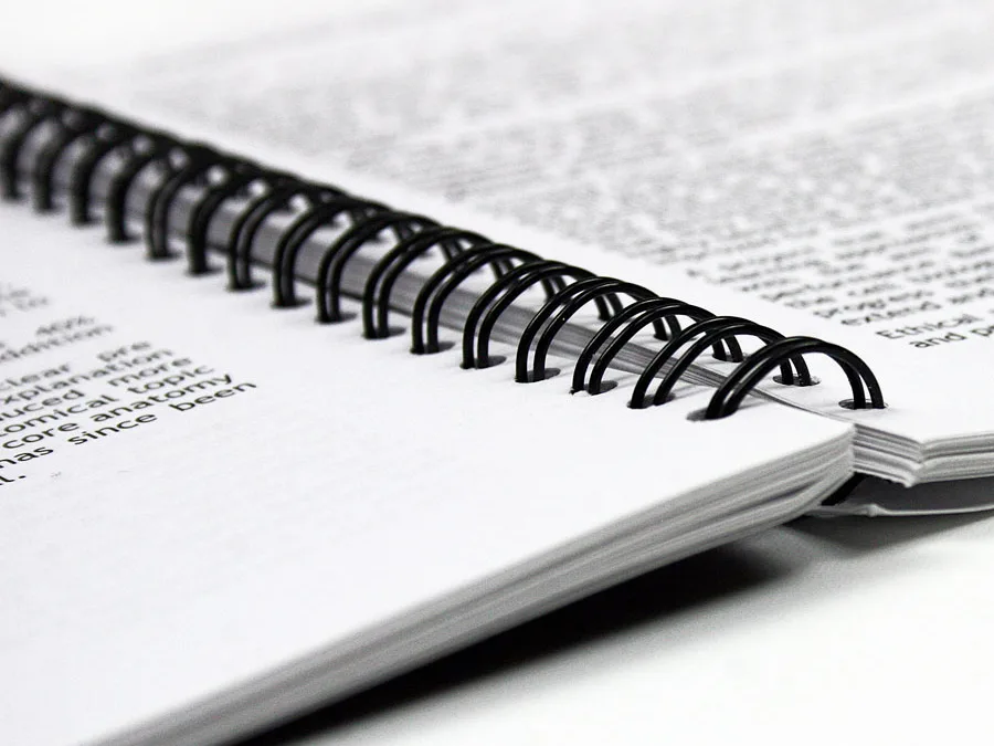 Wire bound document lying completely flat and open at a printed text spread
