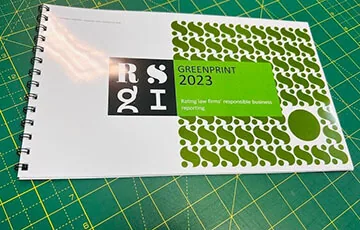 Hand turning a page of a landscape wire bound brochure on a green cutting mat