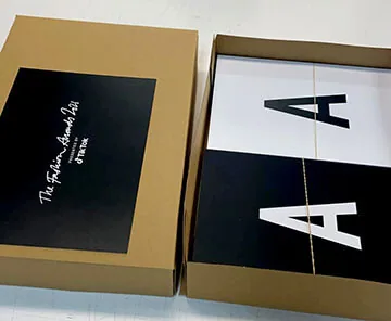 Black and gold presentation box holding printed invitation cards