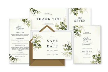 Wedding stationery suite laid out: thank you card, save the date, invitation and kraft envelopes with greenery