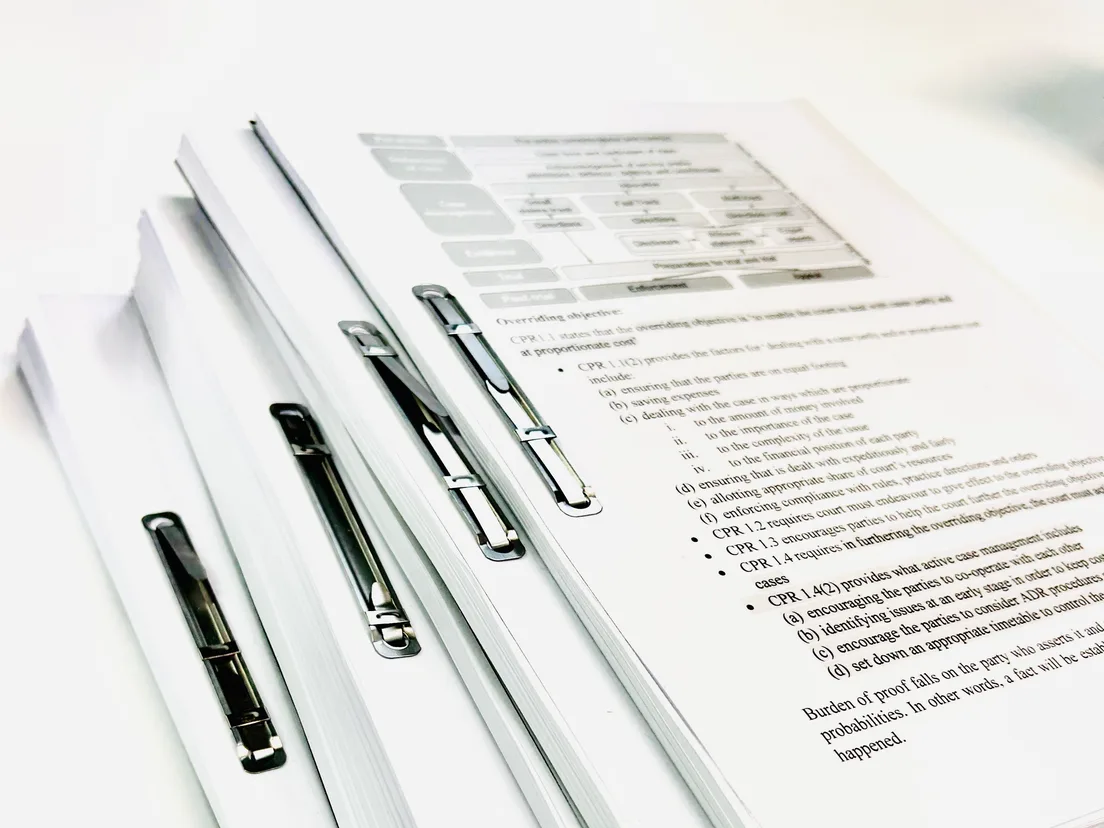 Sets of punched court documents clipped with black Acco fasteners, stacked on a desk