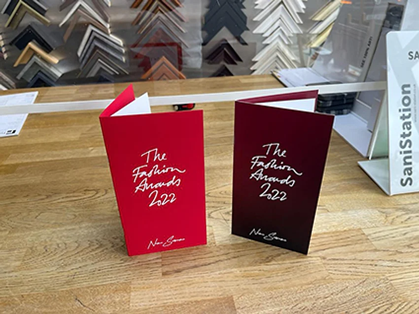 Two foil-blocked Fashion Awards menu covers, one open to show the printed insert held inside