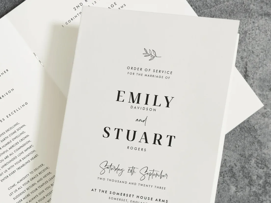 Wedding order of service printed Emily and Stuart, lying on a stone surface
