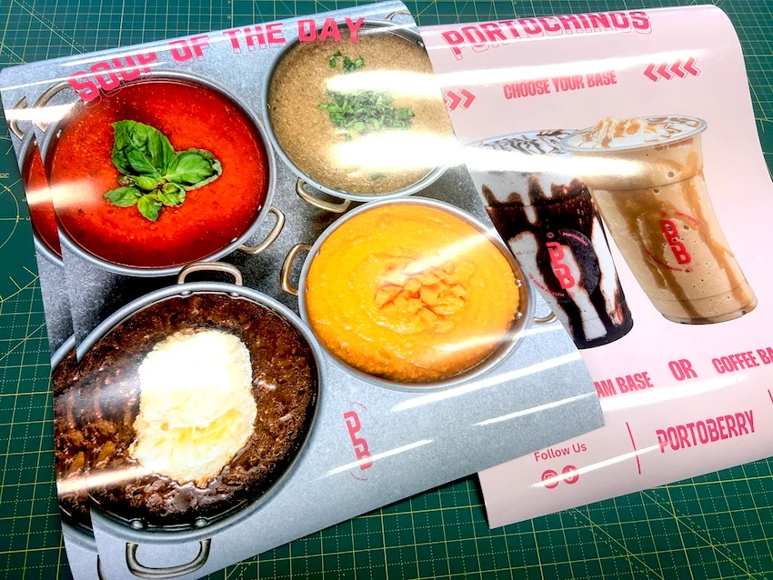 Food photography poster showing dishes in copper pans, on the printer bed with trim marks visible
