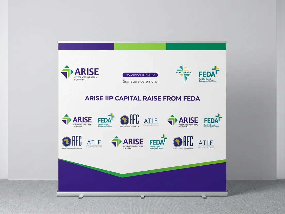 Wide printed backdrop banner with an event title and repeated sponsor logos, on a roller stand