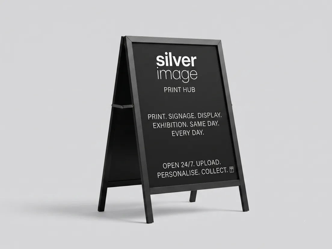 Black A-board pavement sign with a printed panel, standing on a plain floor
