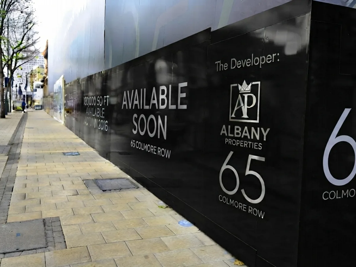 Printed hoarding panels running along a development frontage at street level