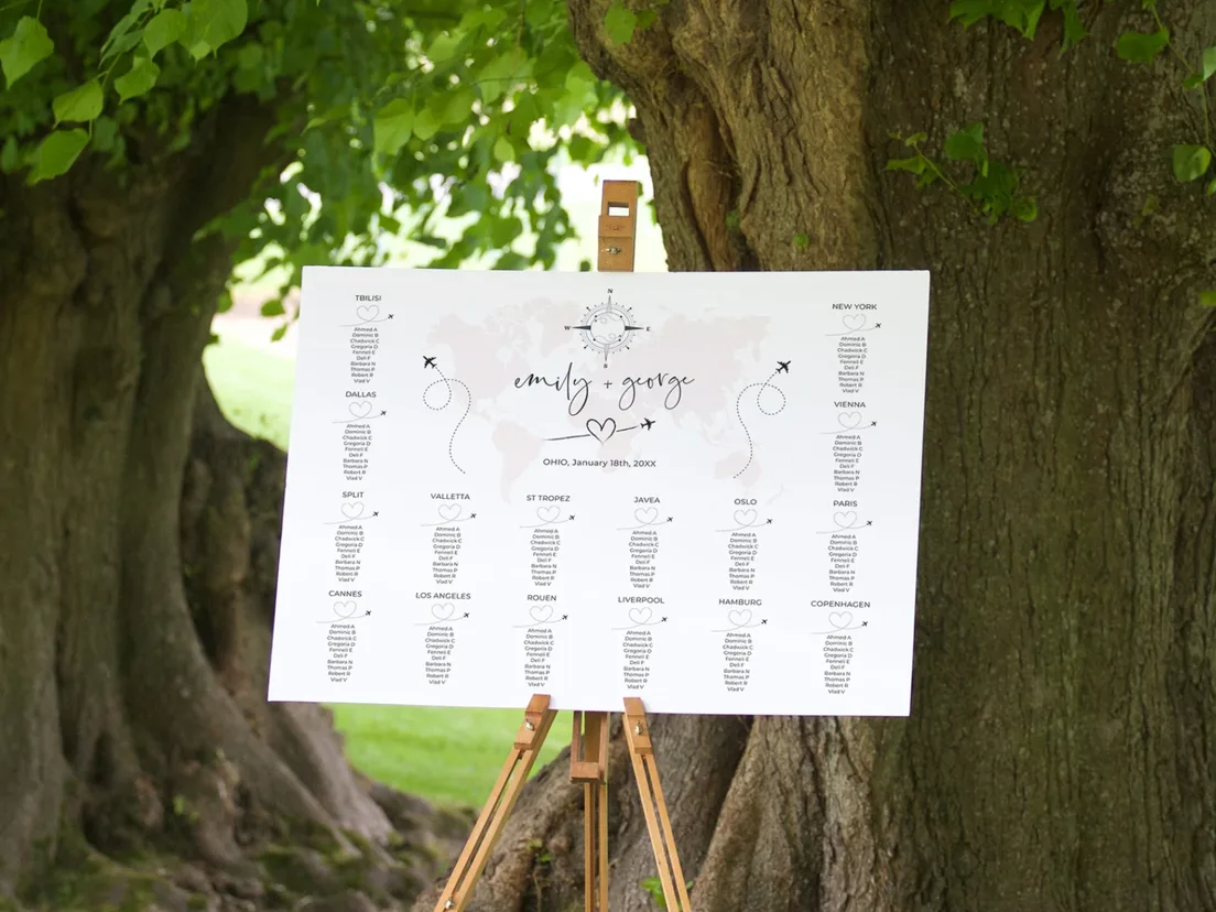 Wedding seating plan on a wooden easel standing outdoors beneath a large tree
